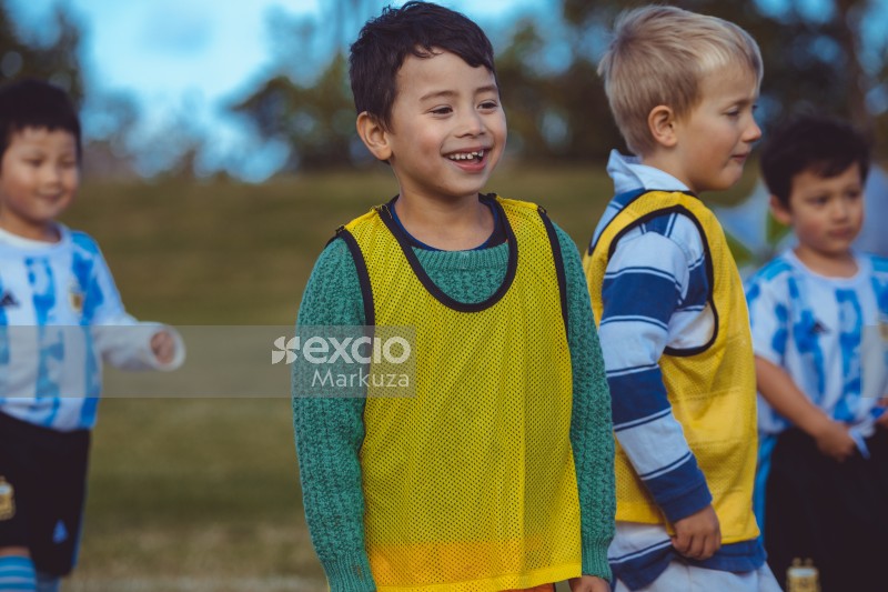Kid with crooked teeth and yellow scrimmage vest laughing at Little Dribblers