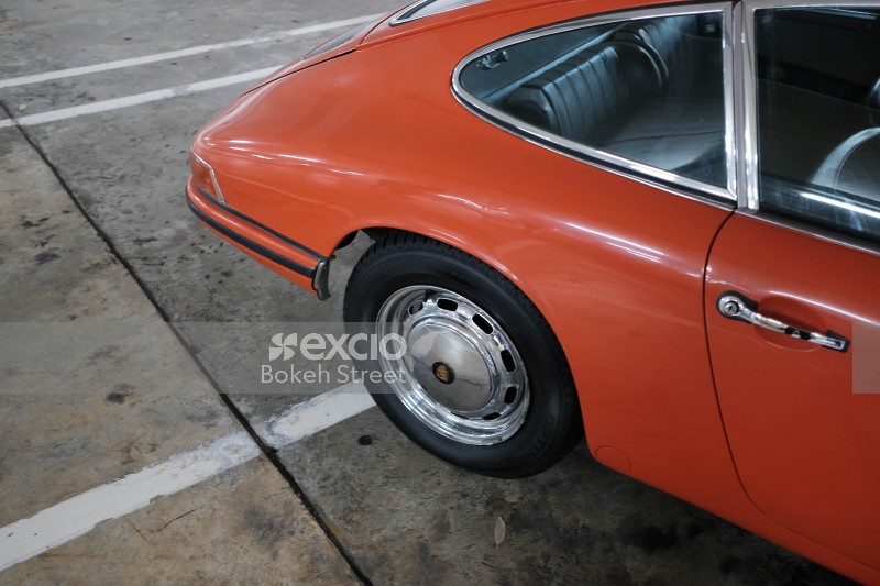 Rear quarter panel and wheel of an orange Porsche