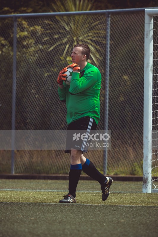 Goalkeeper wearing orange gloves holding ball - Sports Zone sunday league
