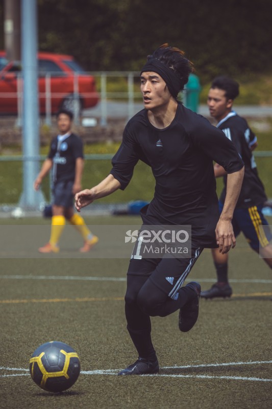 Asian player wearing hairband playing football - Sports Zone sunday league