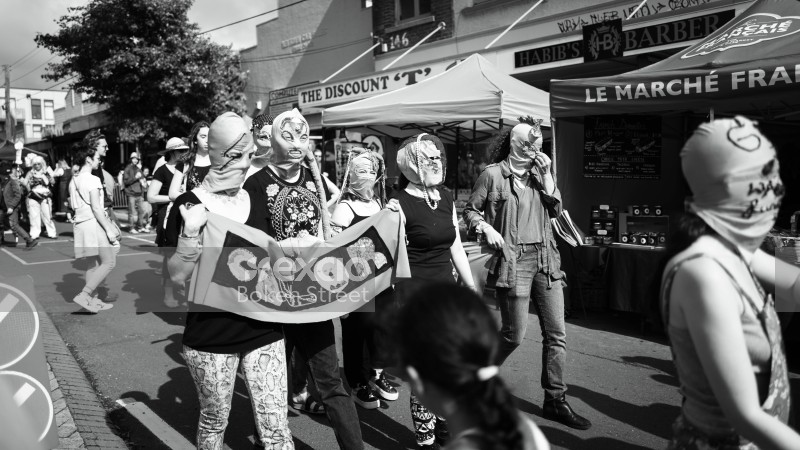 Women in masks hold a banner at Newtown festival 2021 black and white