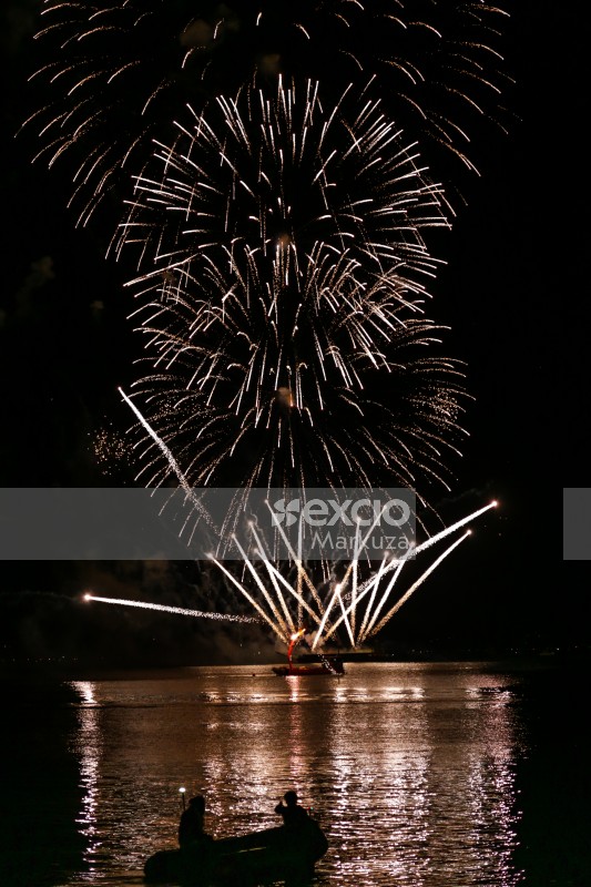 Silver fireworks flares light up sea