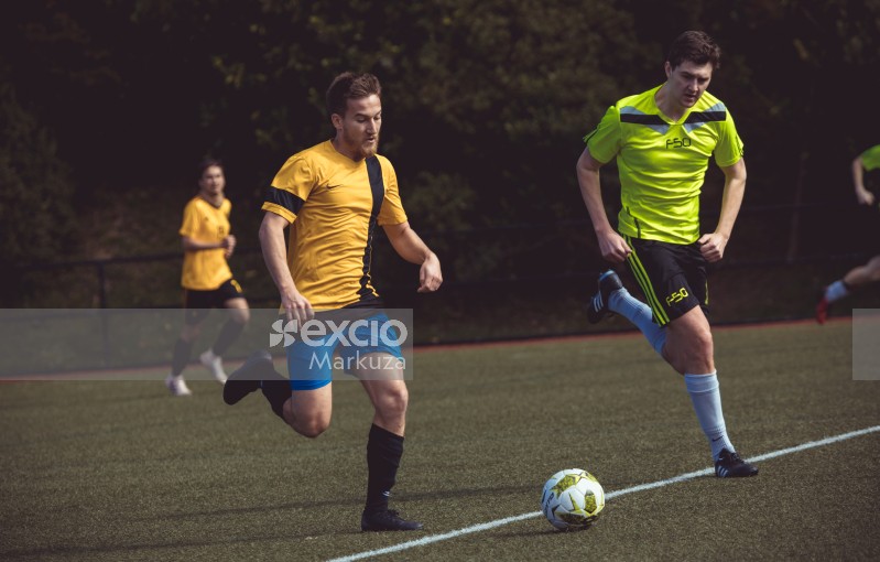 Player in yellow Nike and neon green Adidas shirt following football - Sports Zone sunday league