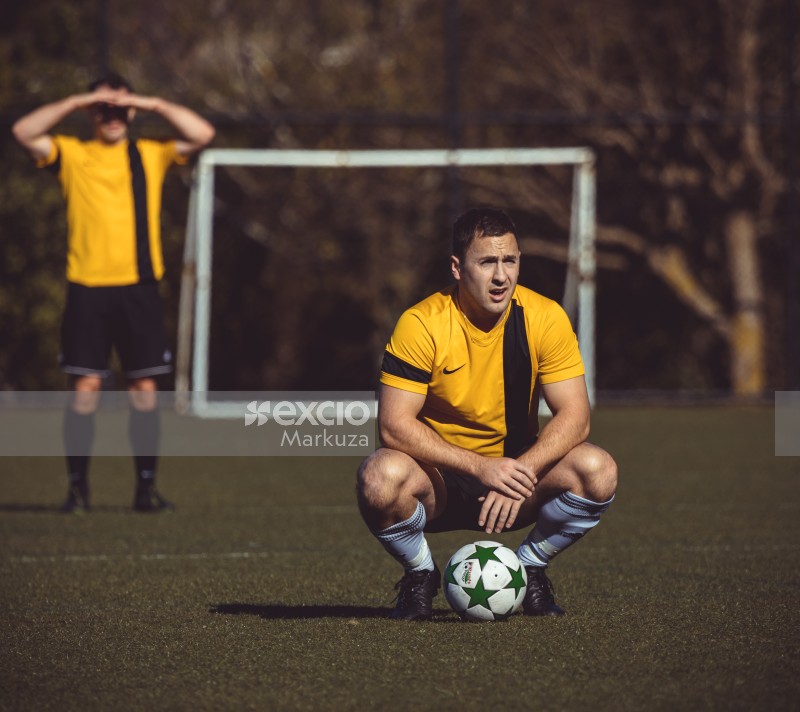 Player in yellow shirt squatting on the field - Sports Zone sunday league