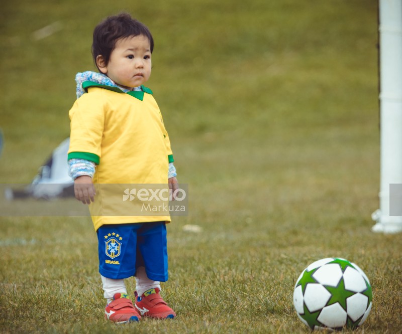Asian kid wearing Brasil kit and red shoes - Little Dribblers