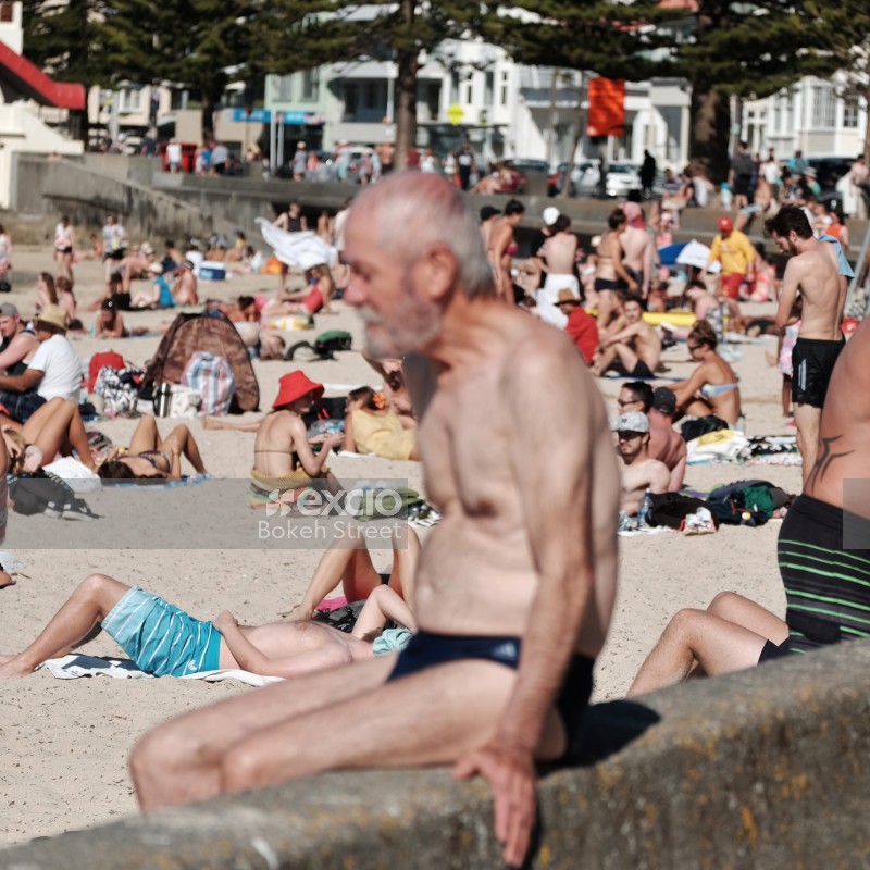 Old guy and a beach crowded with sunbathers bokeh