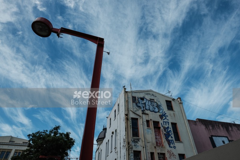 Partly cloudy sky and a graffitied building Cuba Street