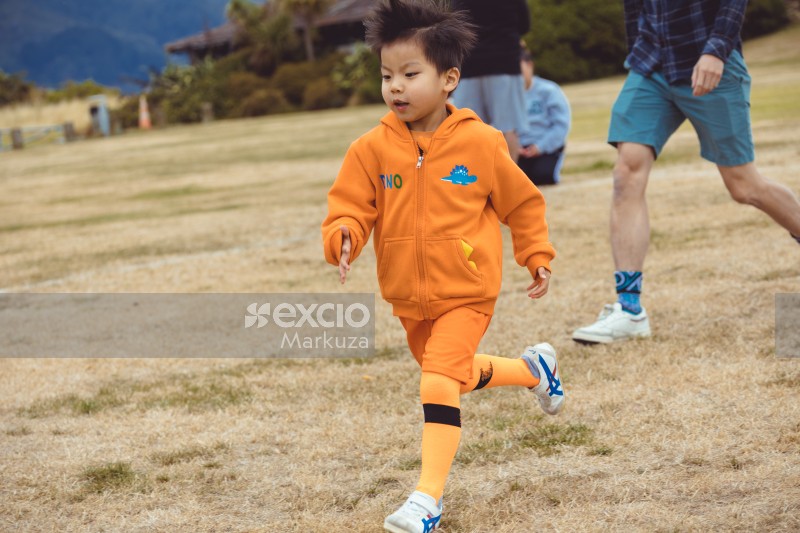 Asian kid in orange hoodie at Little Dribblers soccer game