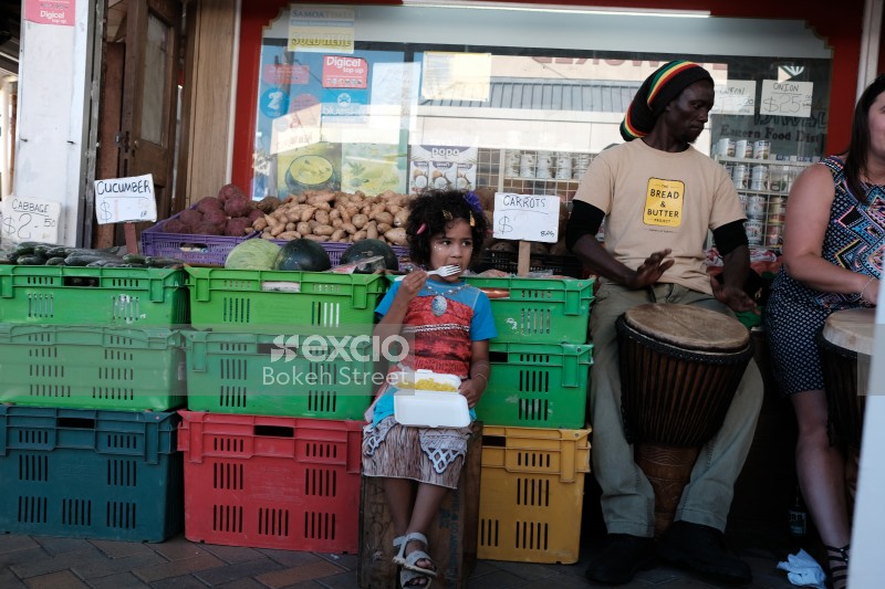 Little girl produce stall eating lunch djembe drum
