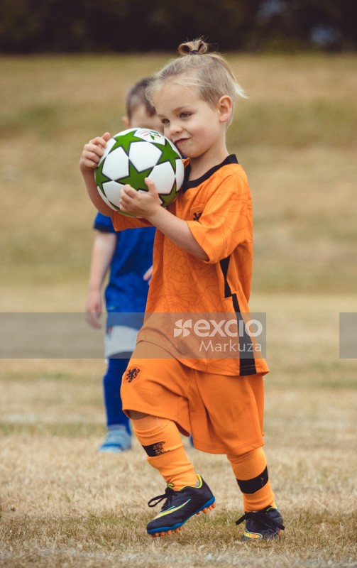 Girl in Netherland kit carrying football at Little Dribblers