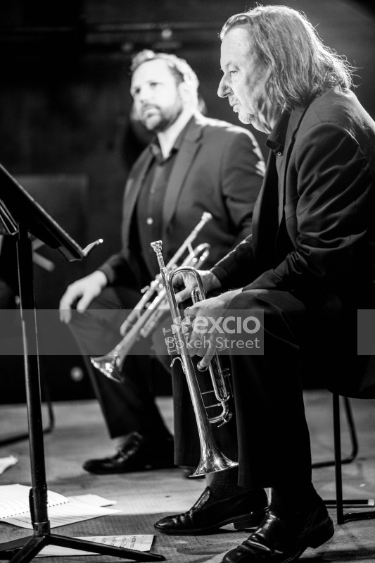 People sitting on a stage in a classical concert holding trumpets black and white