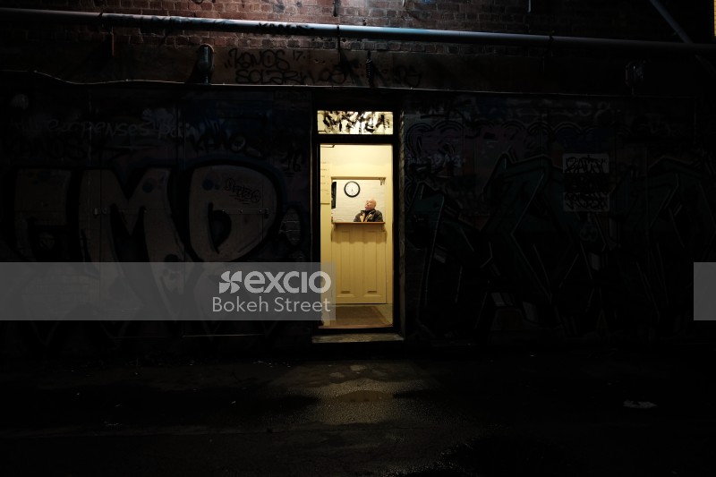 Old bald man sitting inside a graffitied building