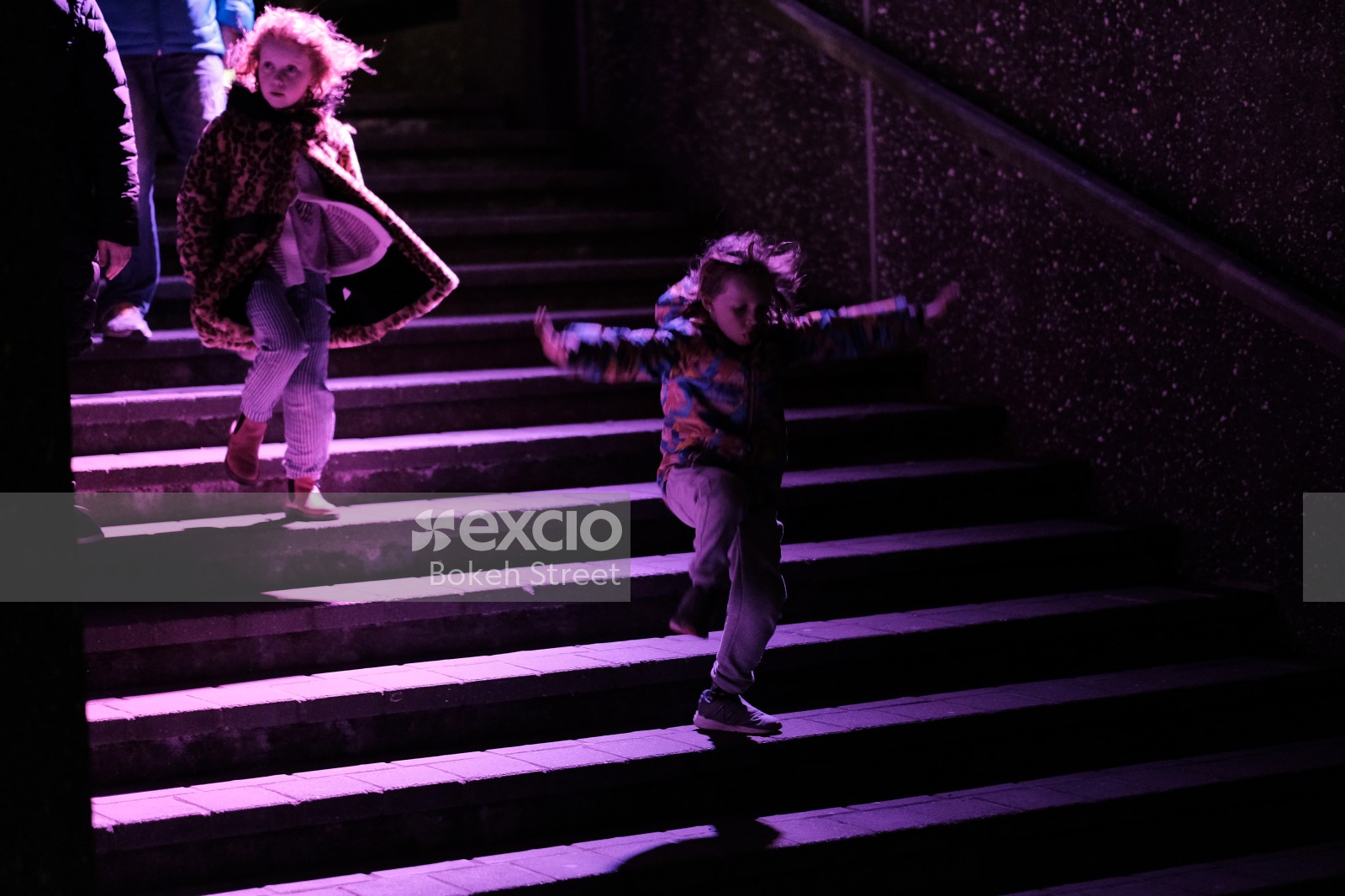 Children descending on purple lit steps