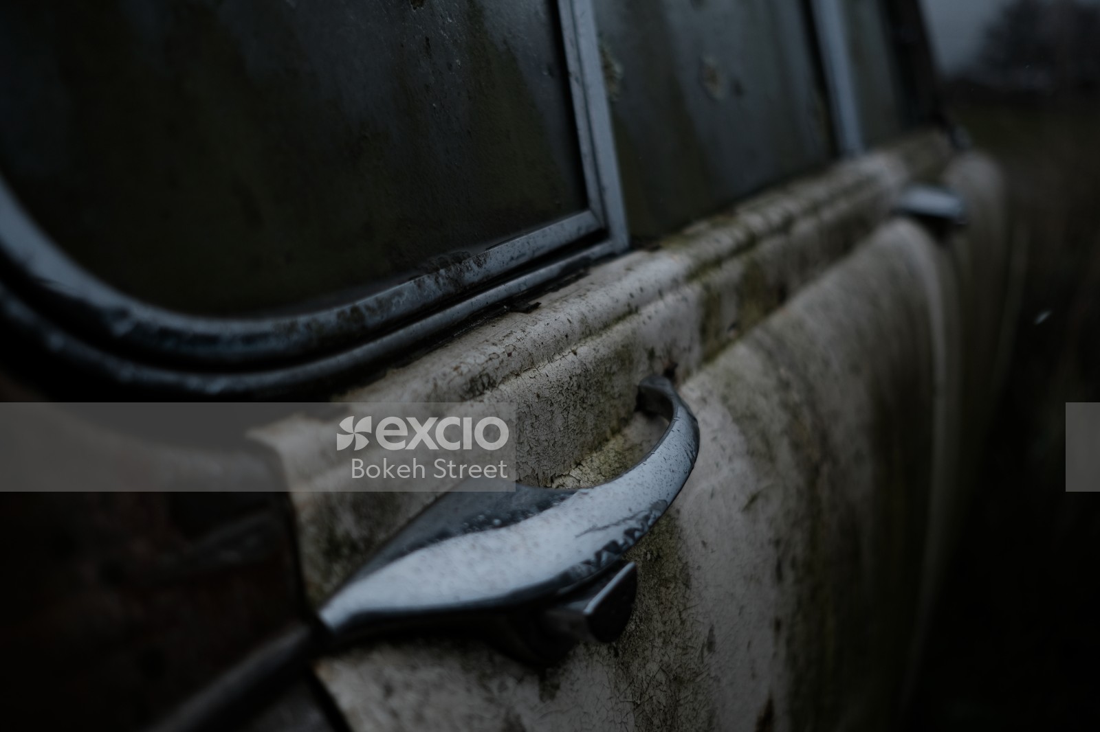 Door handle of an old mouldy white car in Christchurch bokeh