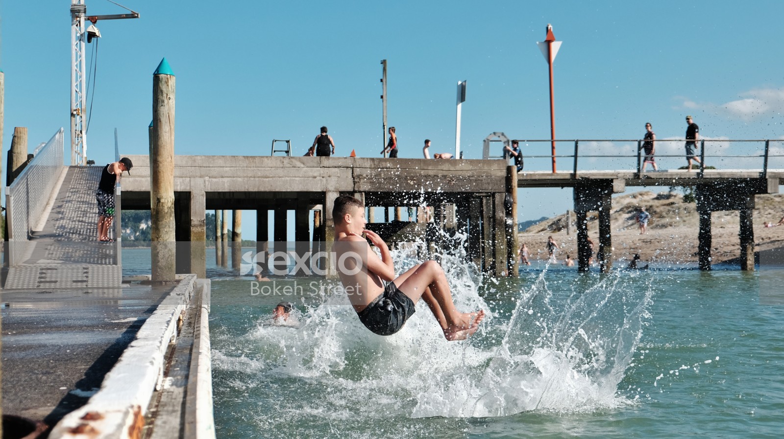 Child dive bombing from pier at the beach 