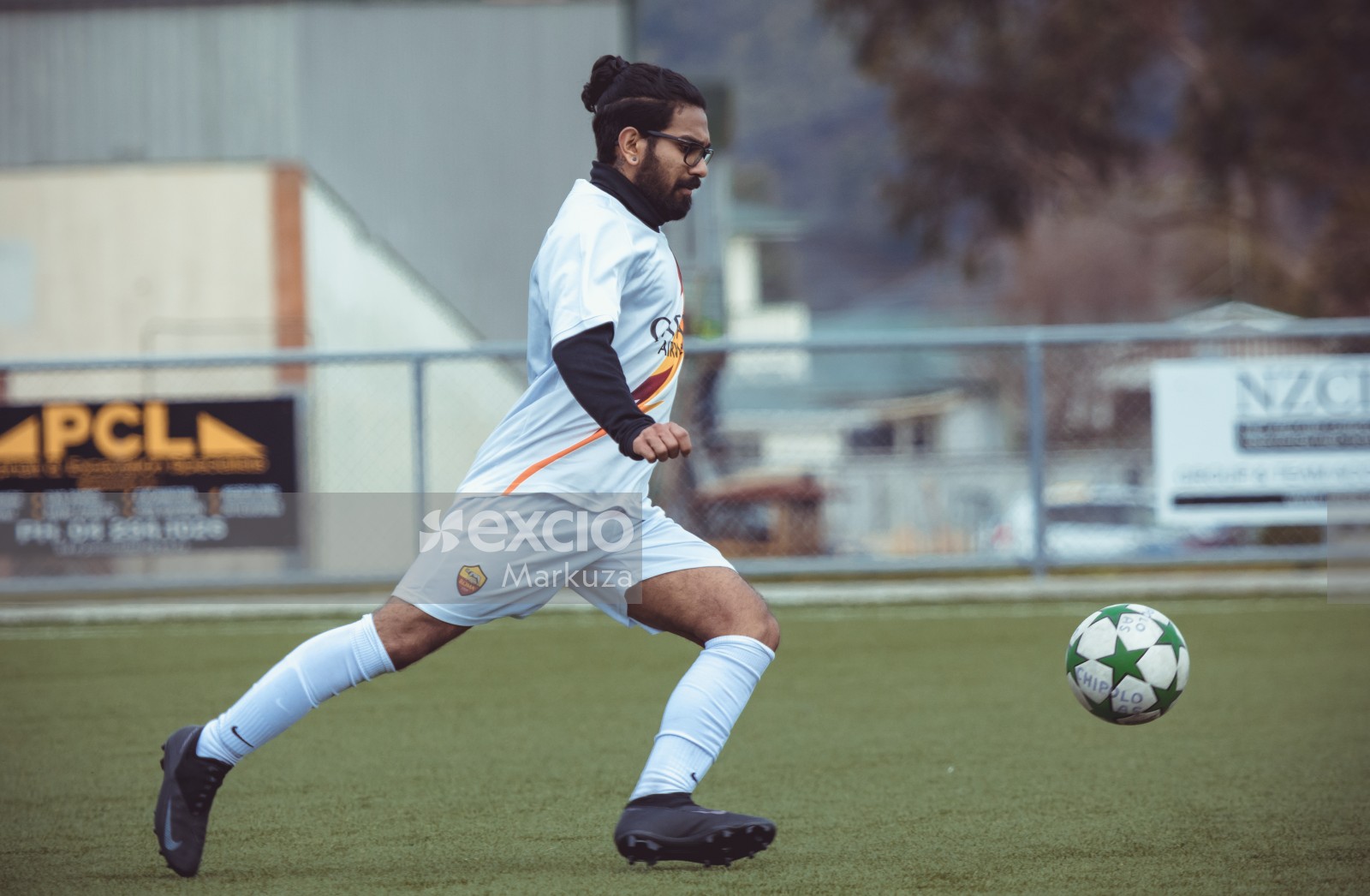 Guy in glasses and man bun running after the ball - Sports Zone sunday league