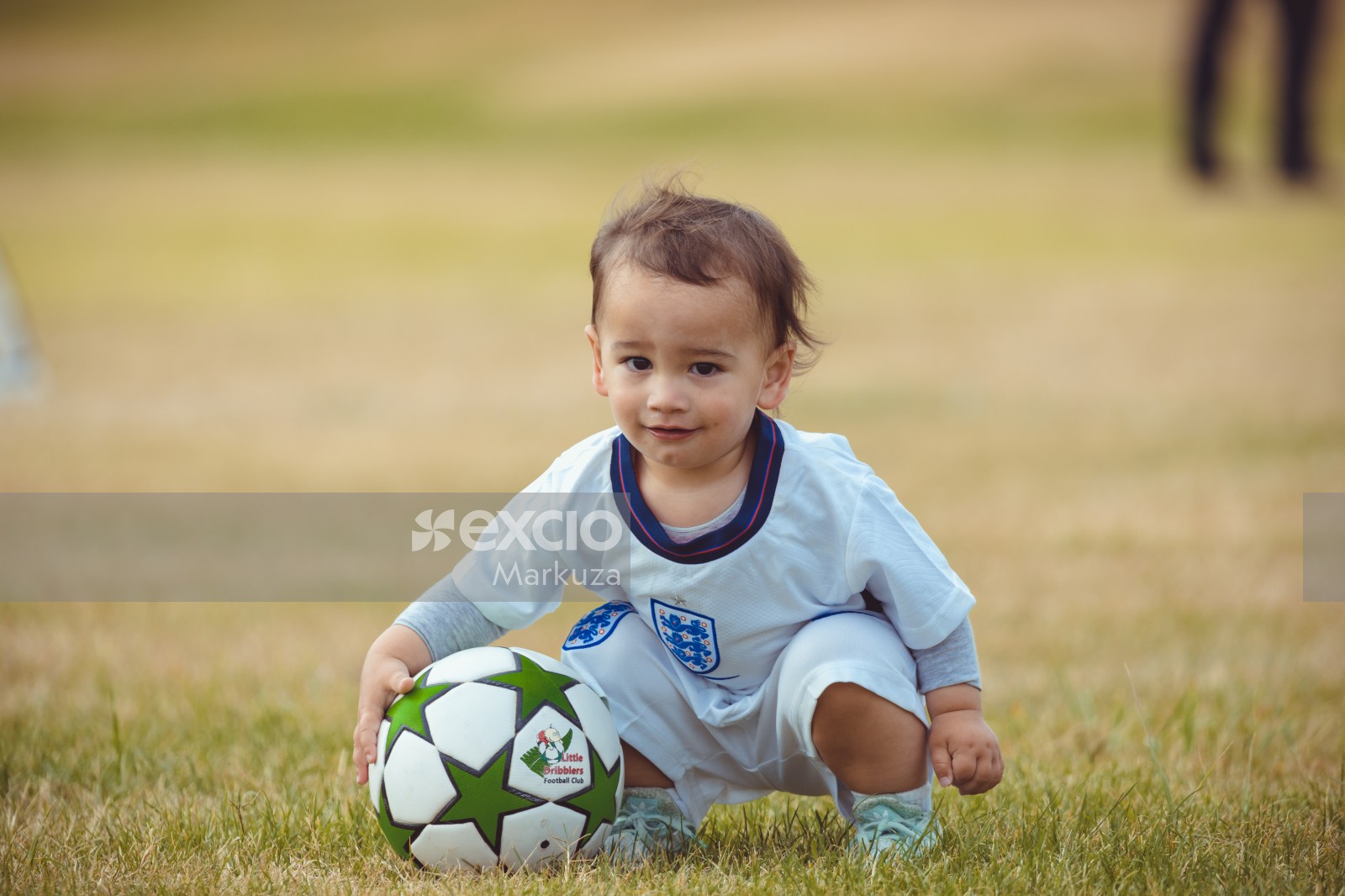 Young boy squatting with a football - Little Dribblers