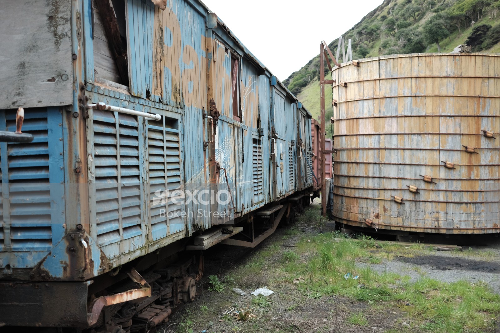 Abandoned old blue freight bogie and large wooden drum structure