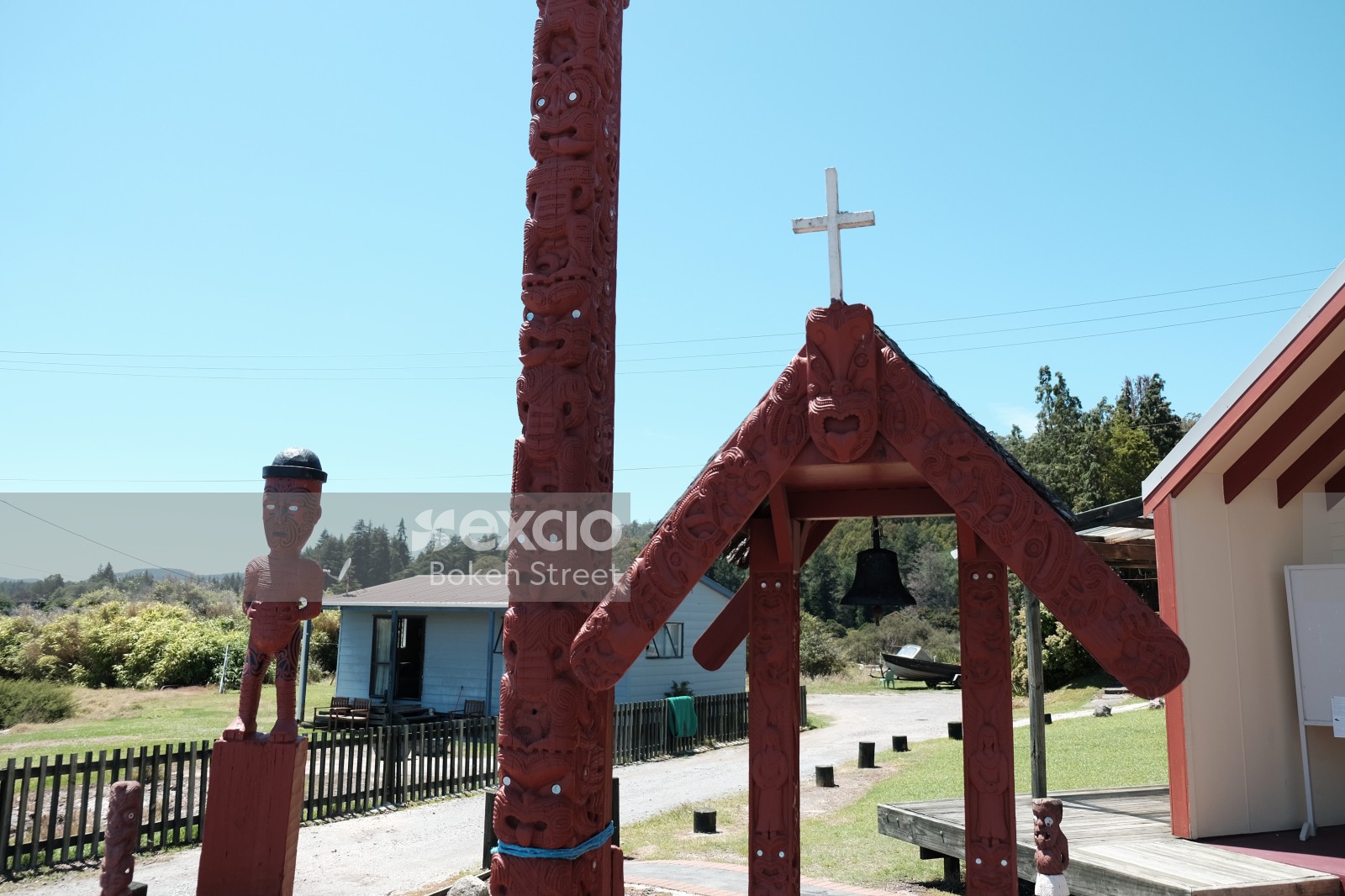 Māori carved totem pole sculpture and Church bell at Whakarewarewa