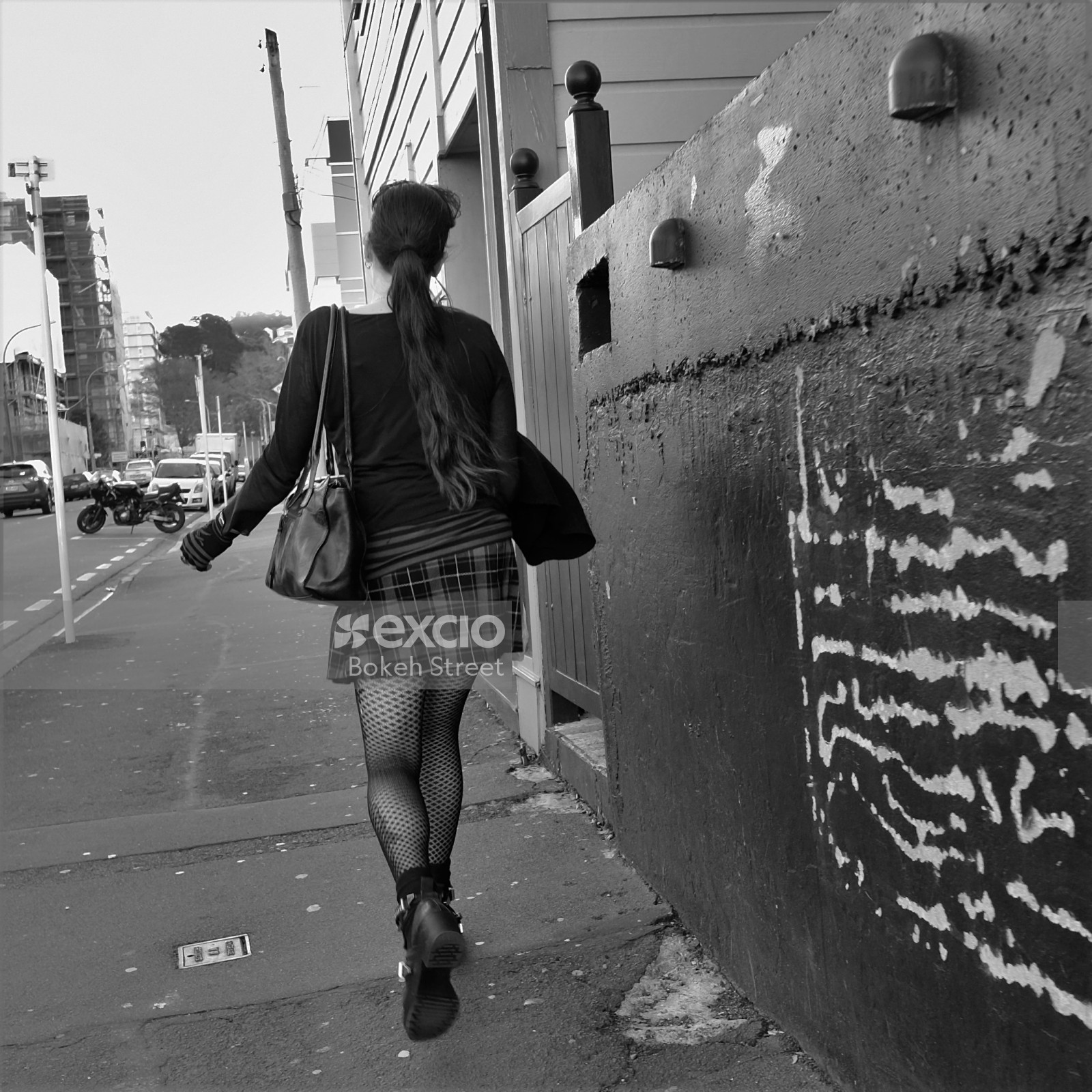 Woman in fishnet tights walking along street
