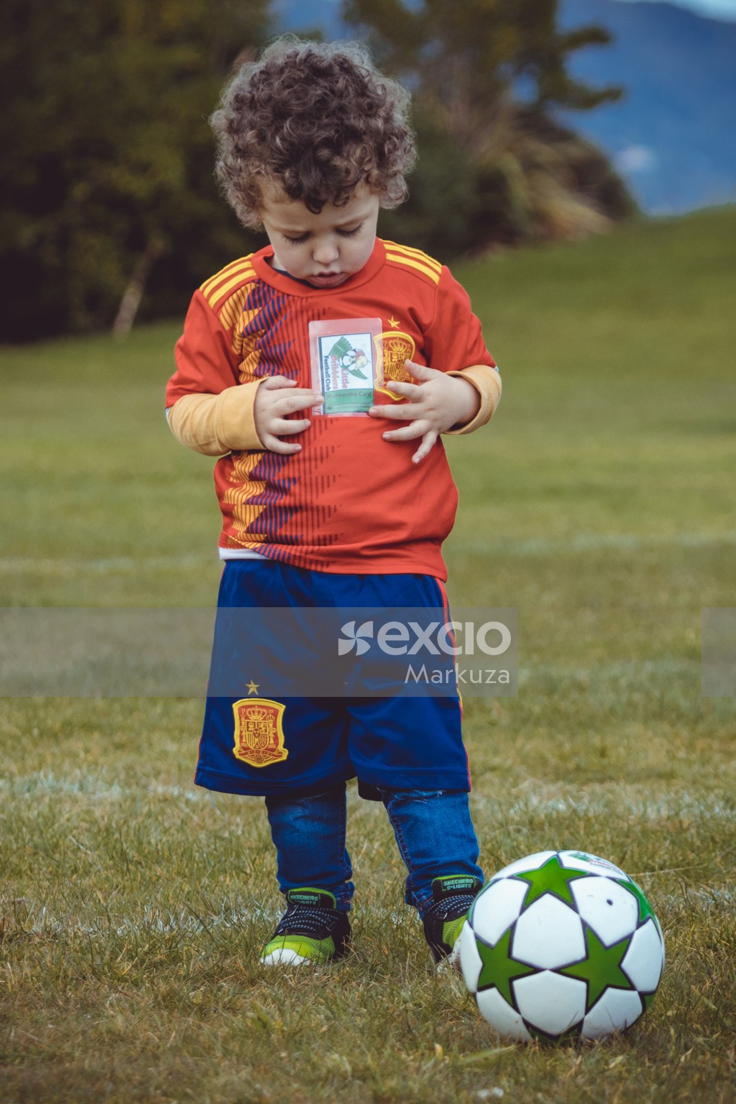 Curly haired boy holding Little Dribblers football club membership card