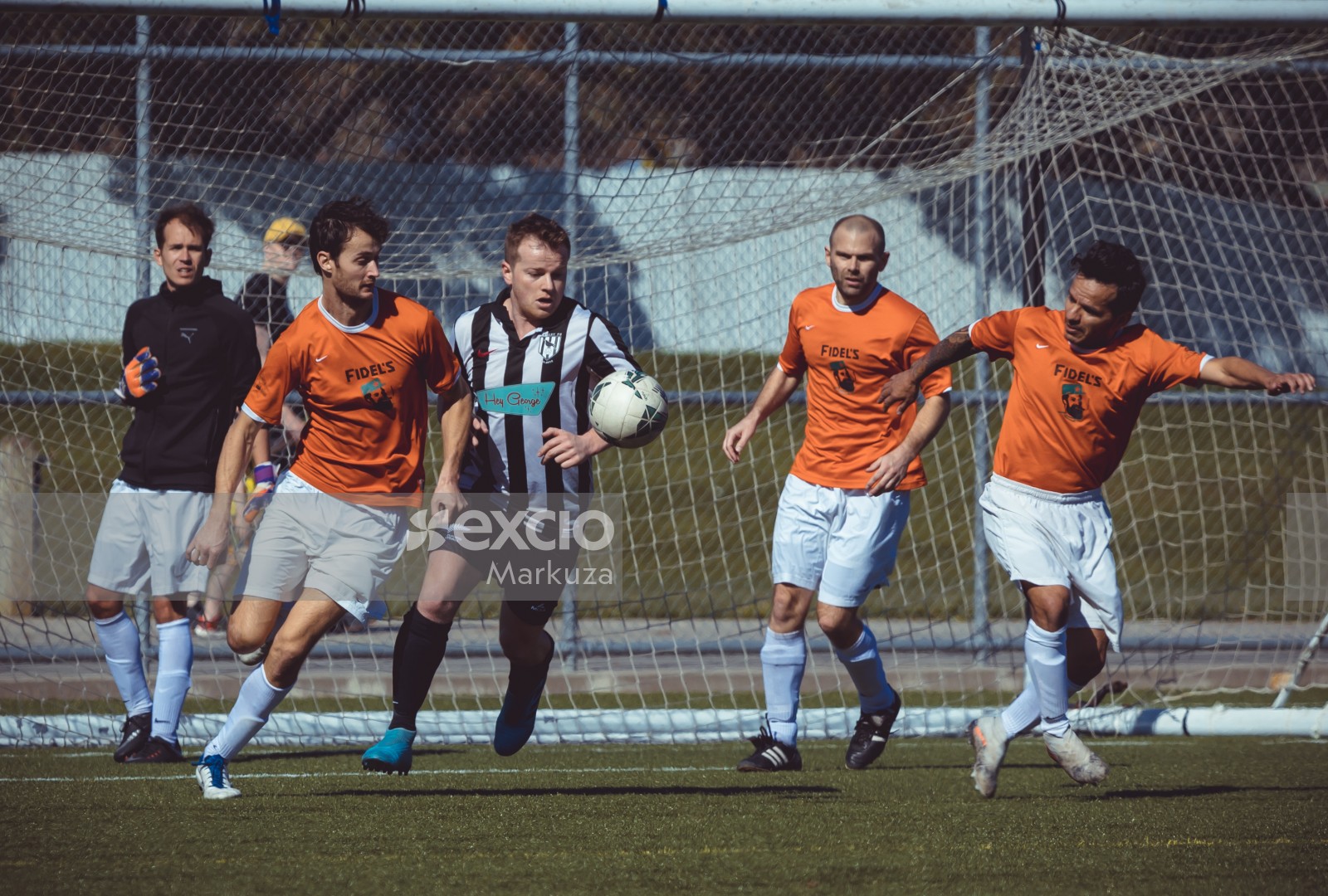 Valley FC player surrounded by players in orange jersey - Sports Zone sunday league