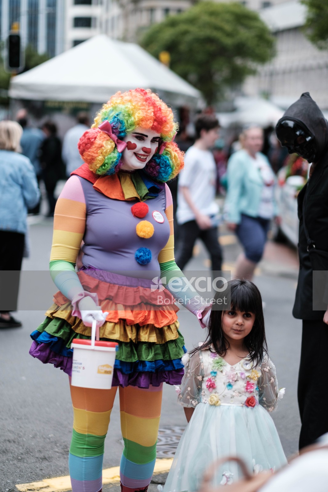 Woman dressed as clown standing with child