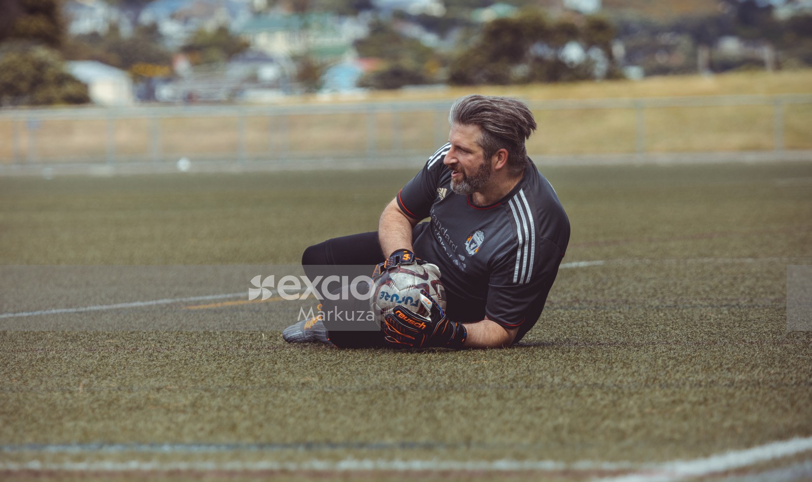 Grey haired goalkeeper on the grass holding football - Sports Zone sunday league