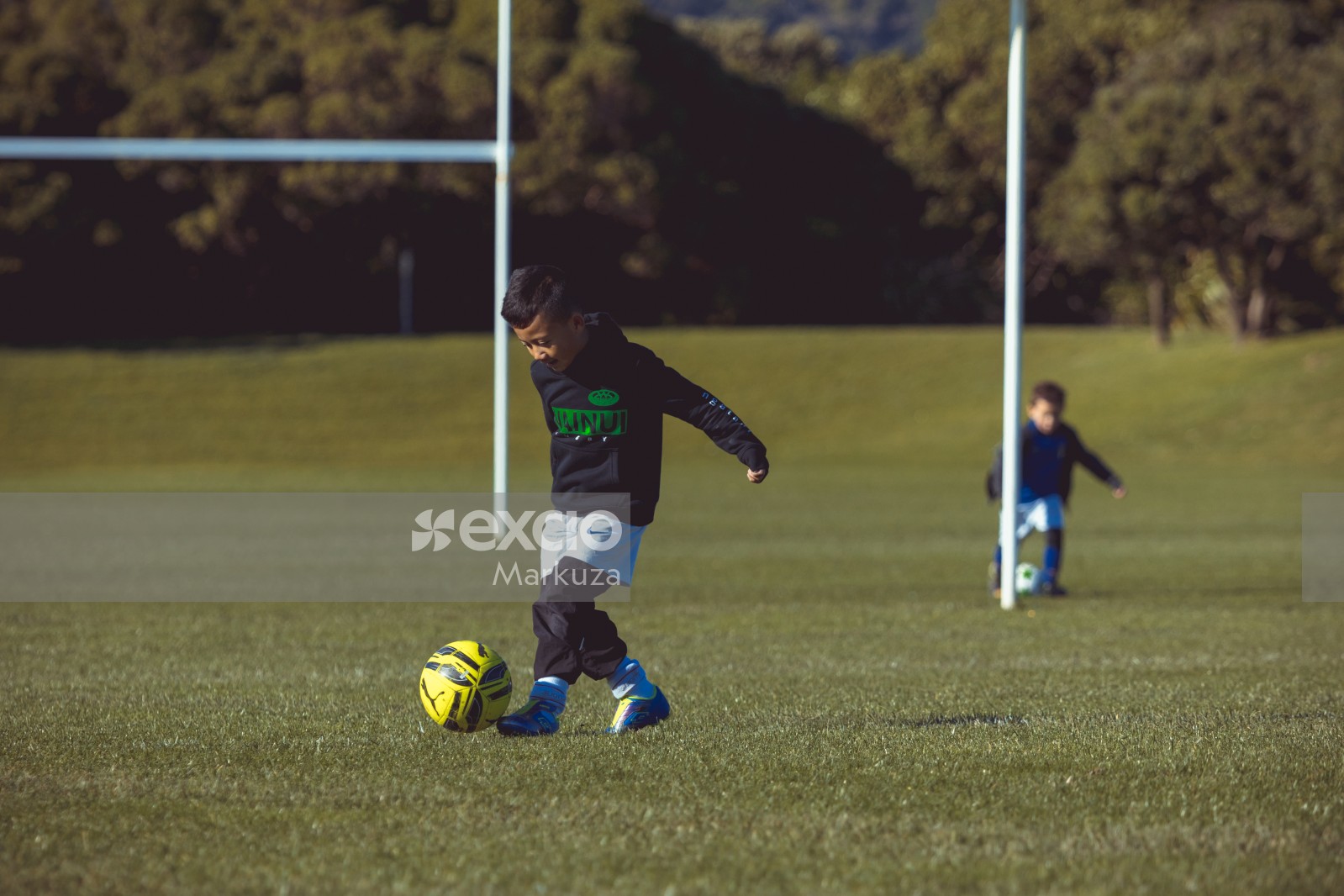 Boy kicking football at Little Dribblers football match