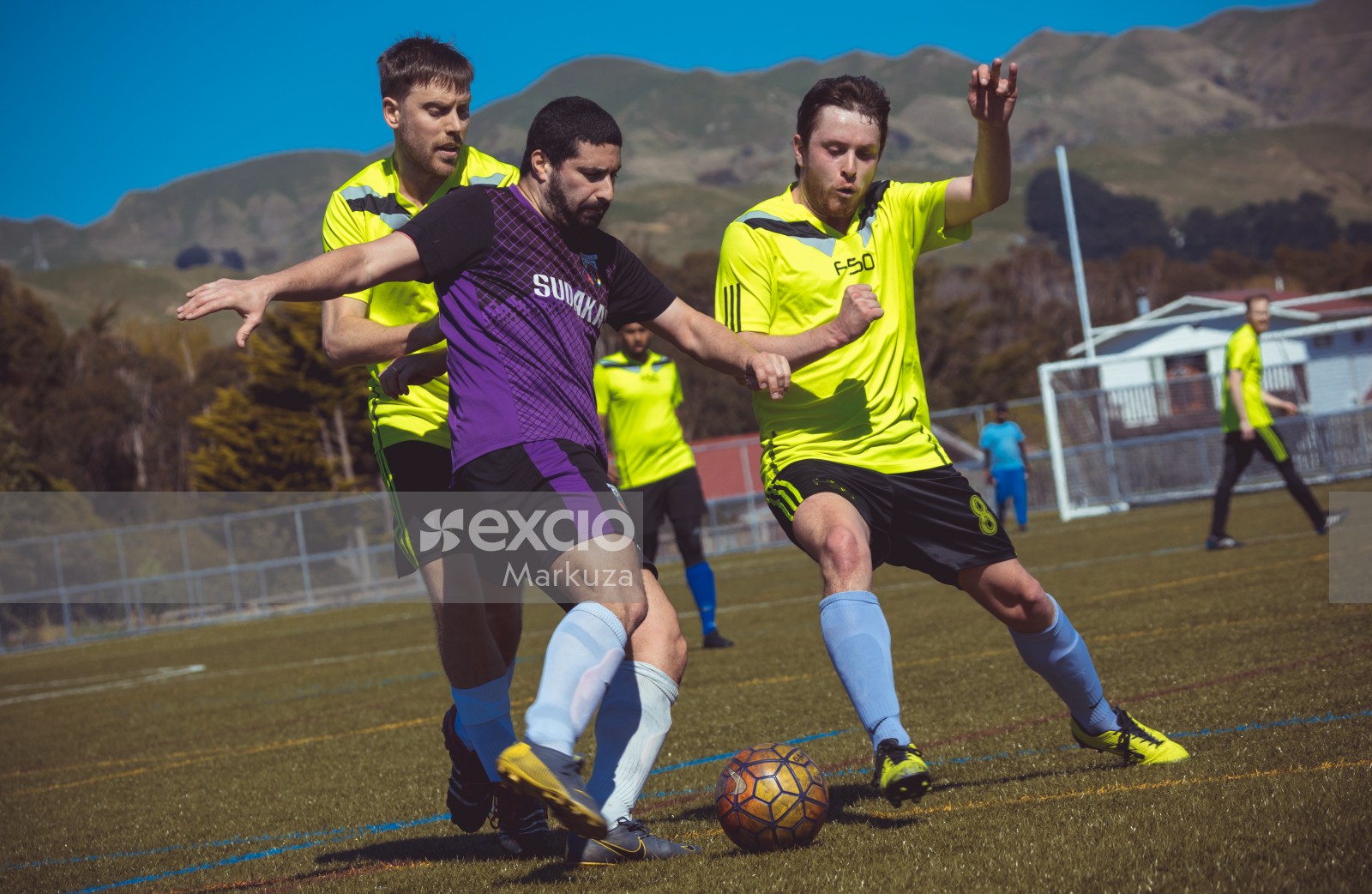 Player in purple shirt defend tackle from two opponents - Sports Zone sunday league