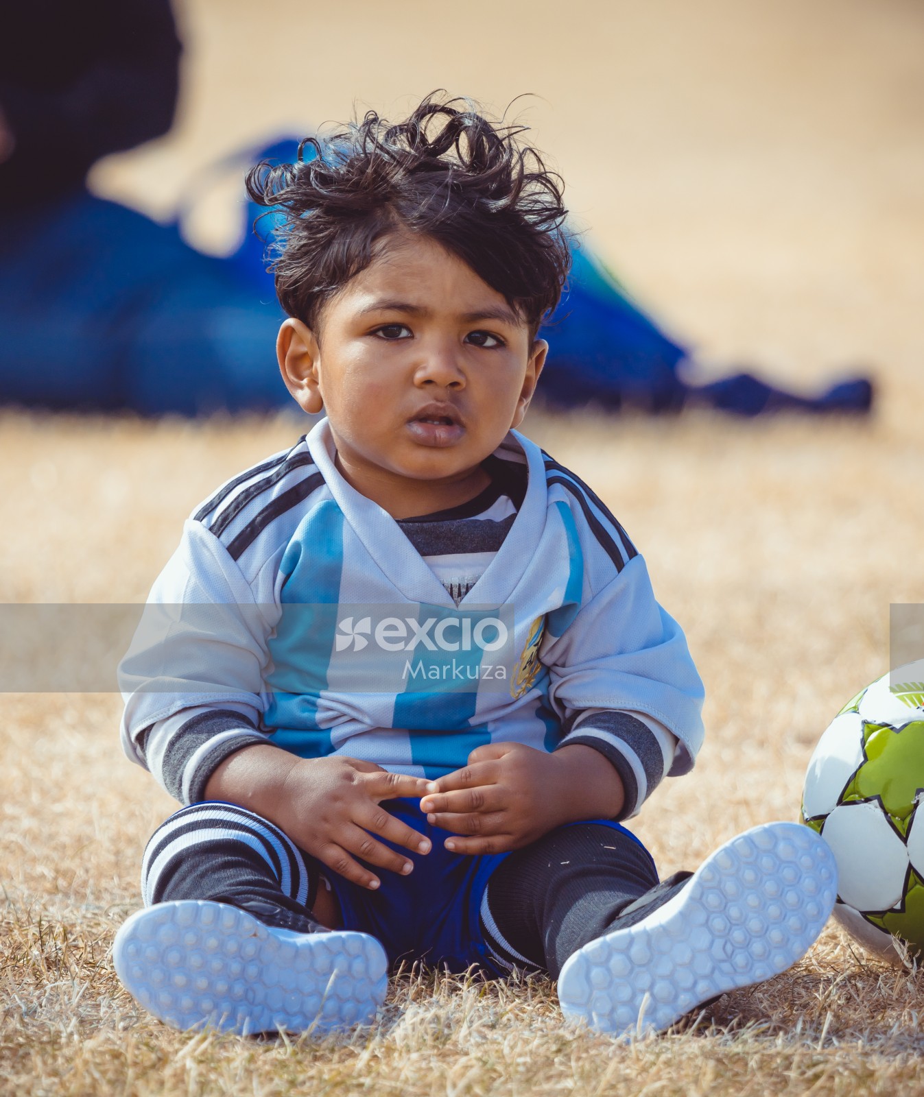 kid in Argentina kit sitting in grass - Little Dribblers