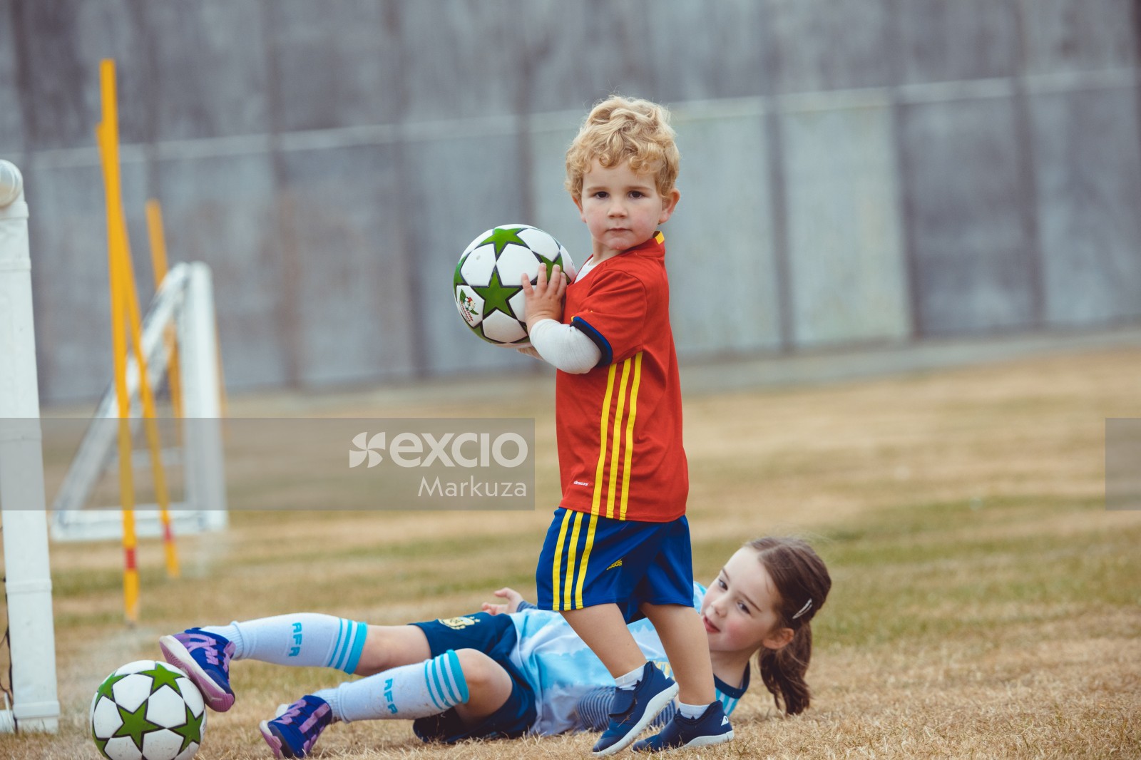 Boy holding a football girl on the grass at Little Dribblers club