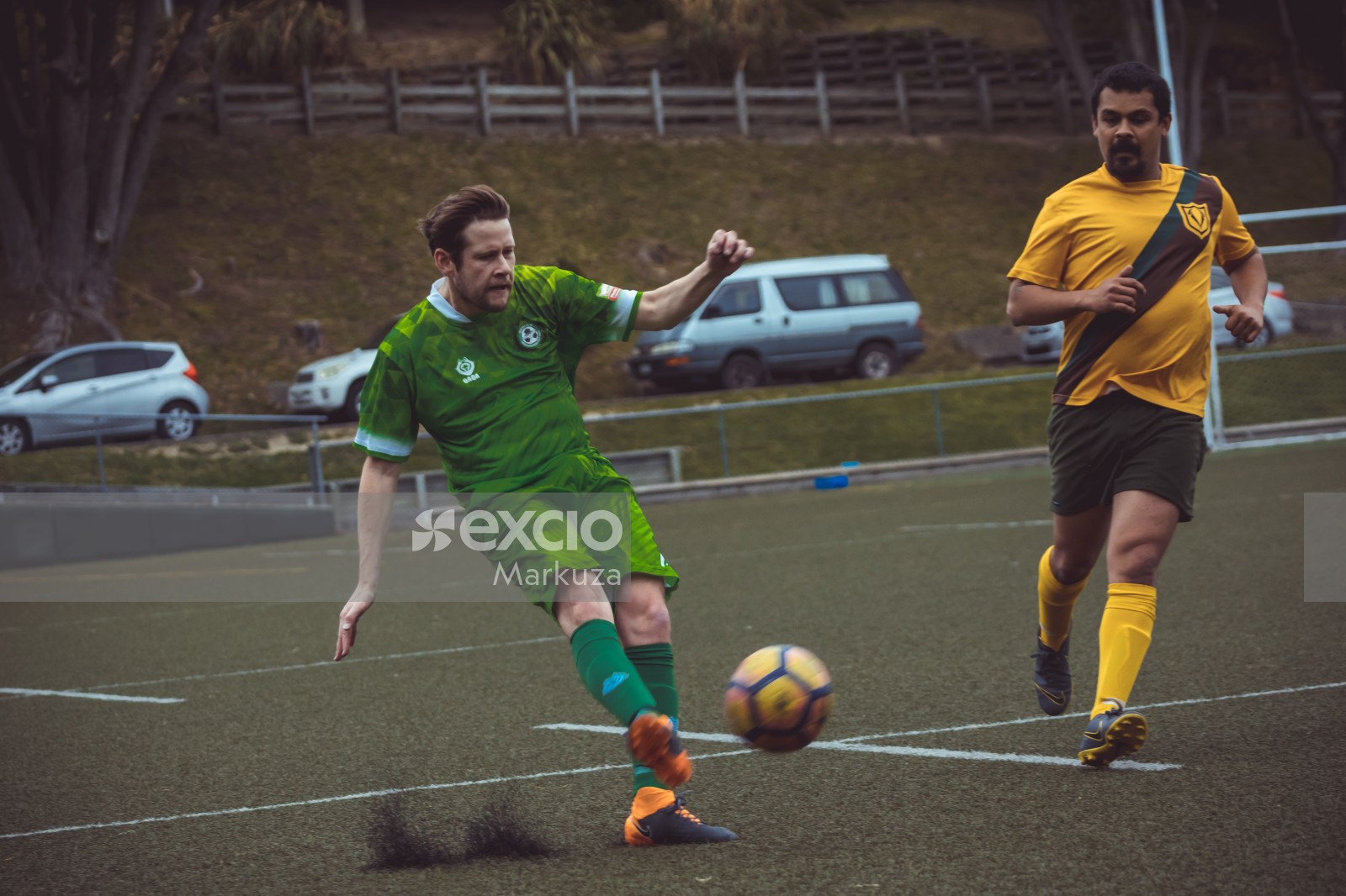 Player in green kit black and orange Nike cleats kicking football - Sports Zone sunday league
