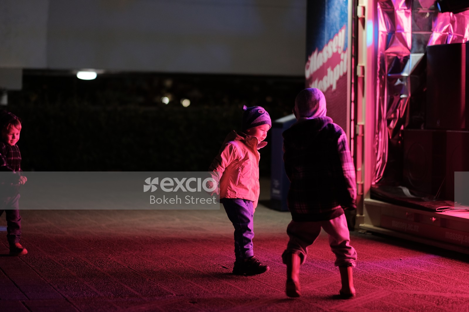 Children playing in pink light on pavement