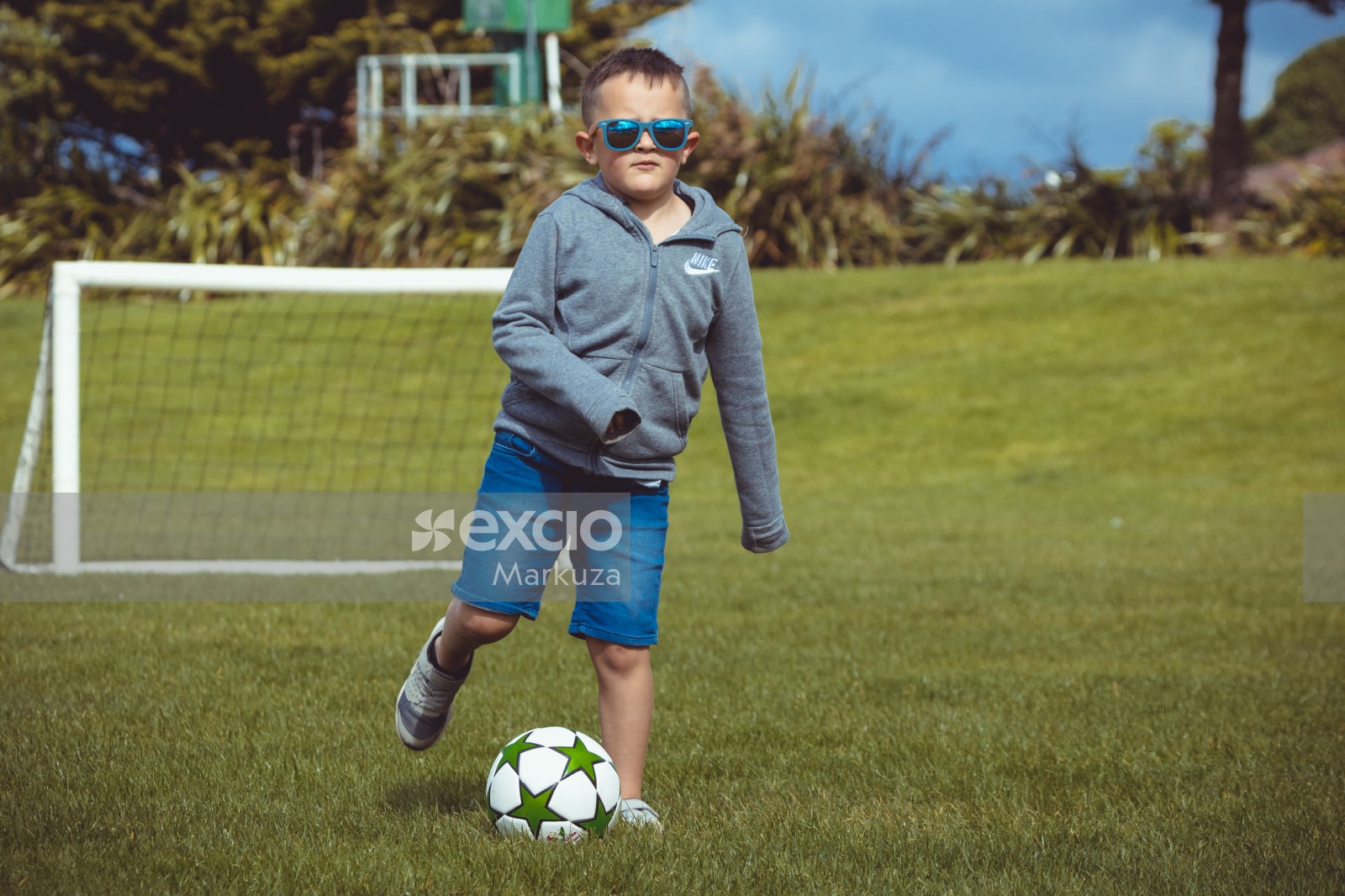 Boy wearing grey Nike hoodie kicking a football - Little Dribblers