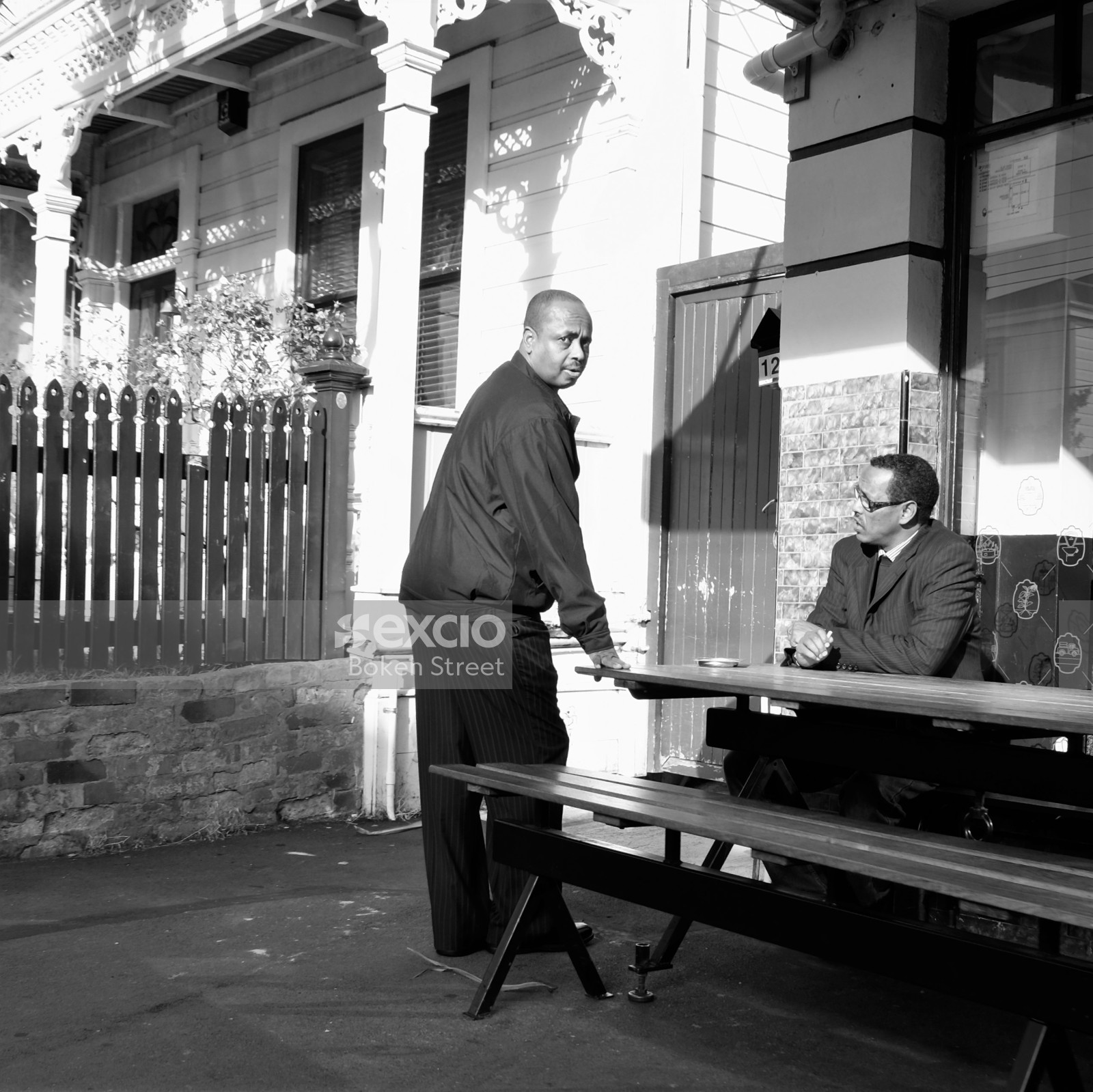 Two dark skinned men having a conversation at the table outdoors in Newtown