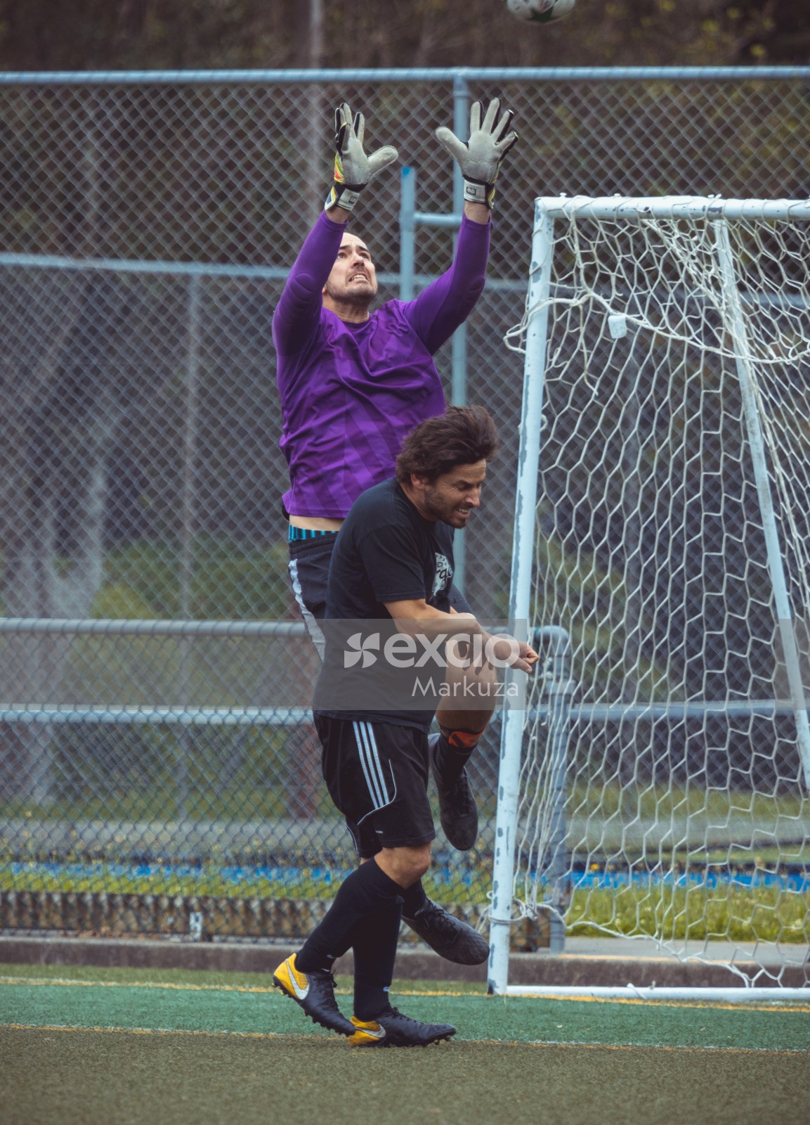 Goalkeeper in purple shirt trying to intercept ball midair - Sports Zone sunday league