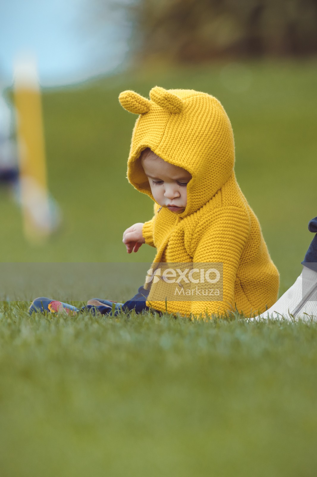 Little child in yellow crochet hoodie with bunny ears