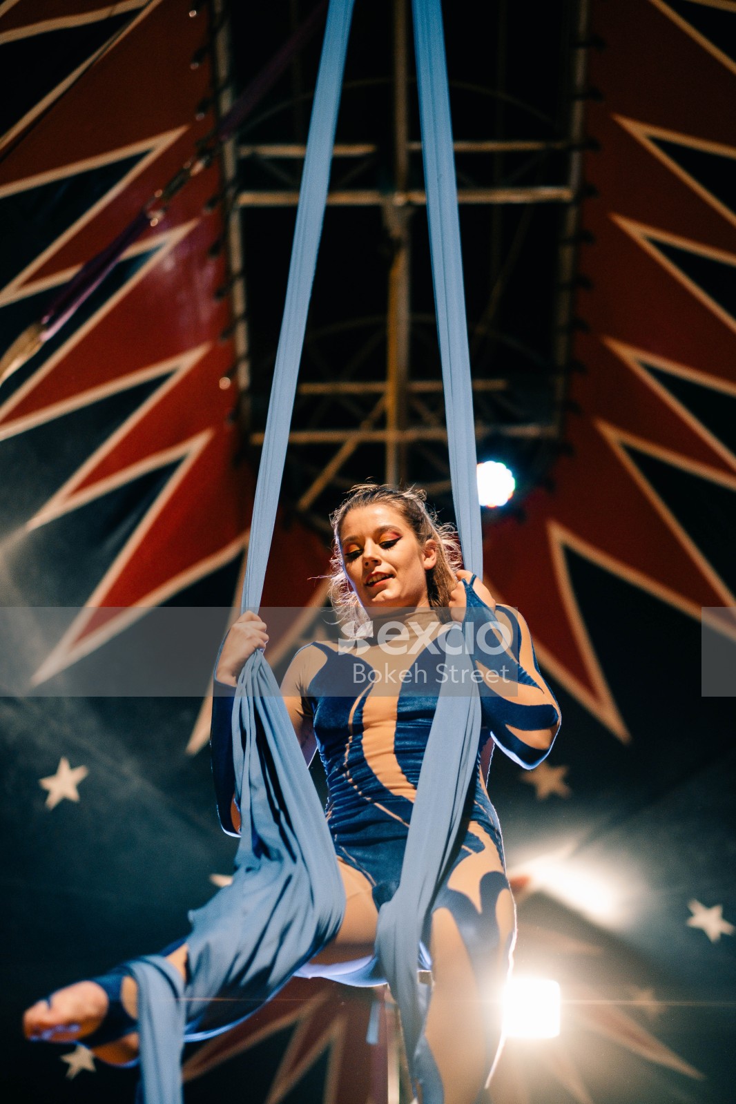 Circus performance by acrobat in blue attire with cloth rope