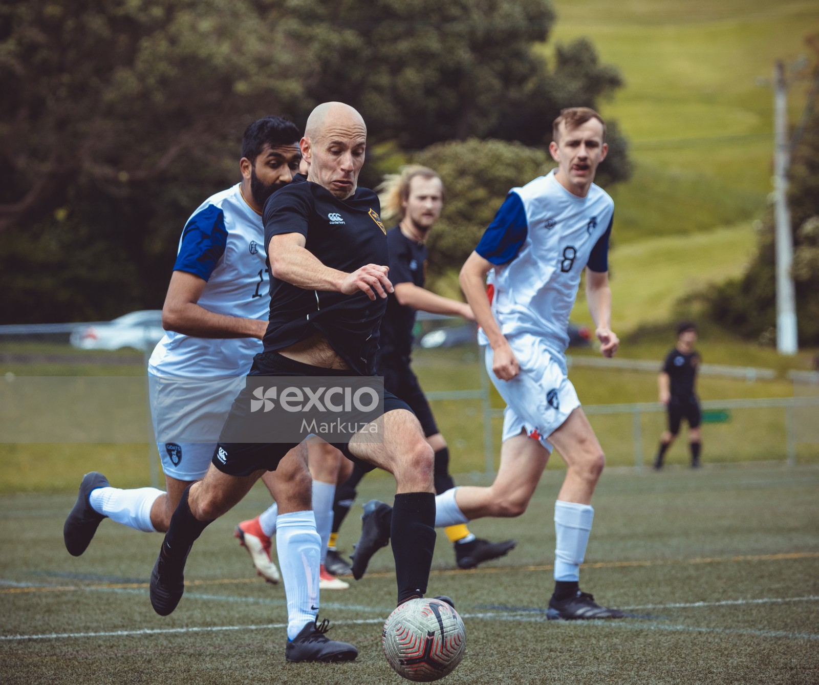 Bald player in black shirt running to score a goal - Sports Zone sunday league