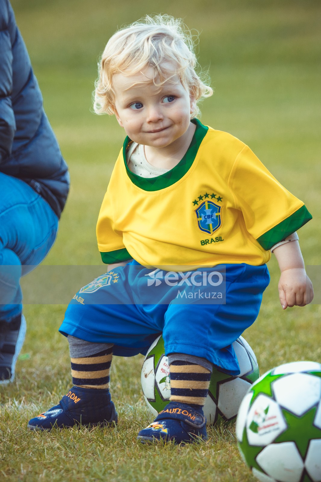 Kid wearing Brasil kit sitting on football - Little Dribblers