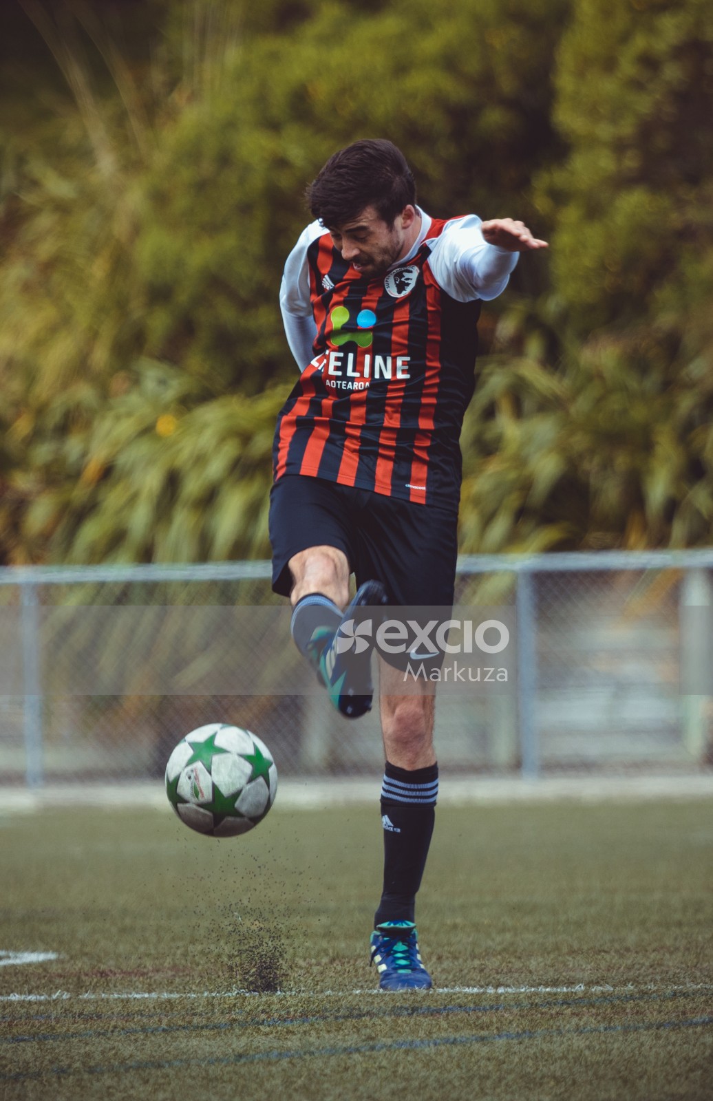 Football player in striped shirt kicks ball - Sports Zone sunday league