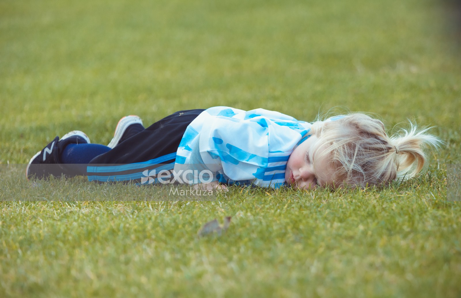 Girl laying face down on grass - Little Dribblers