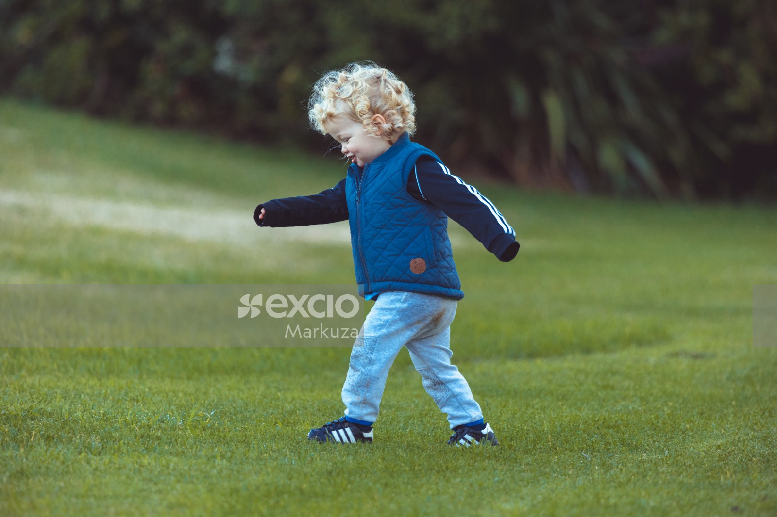 Kid wearing blue vest walking on grass - Little Dribblers