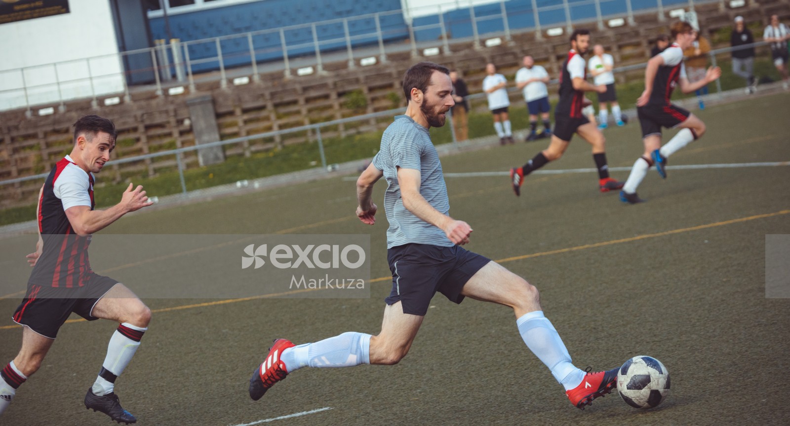 Player in a grey lined shirt running with the football - Sports Zone sunday league