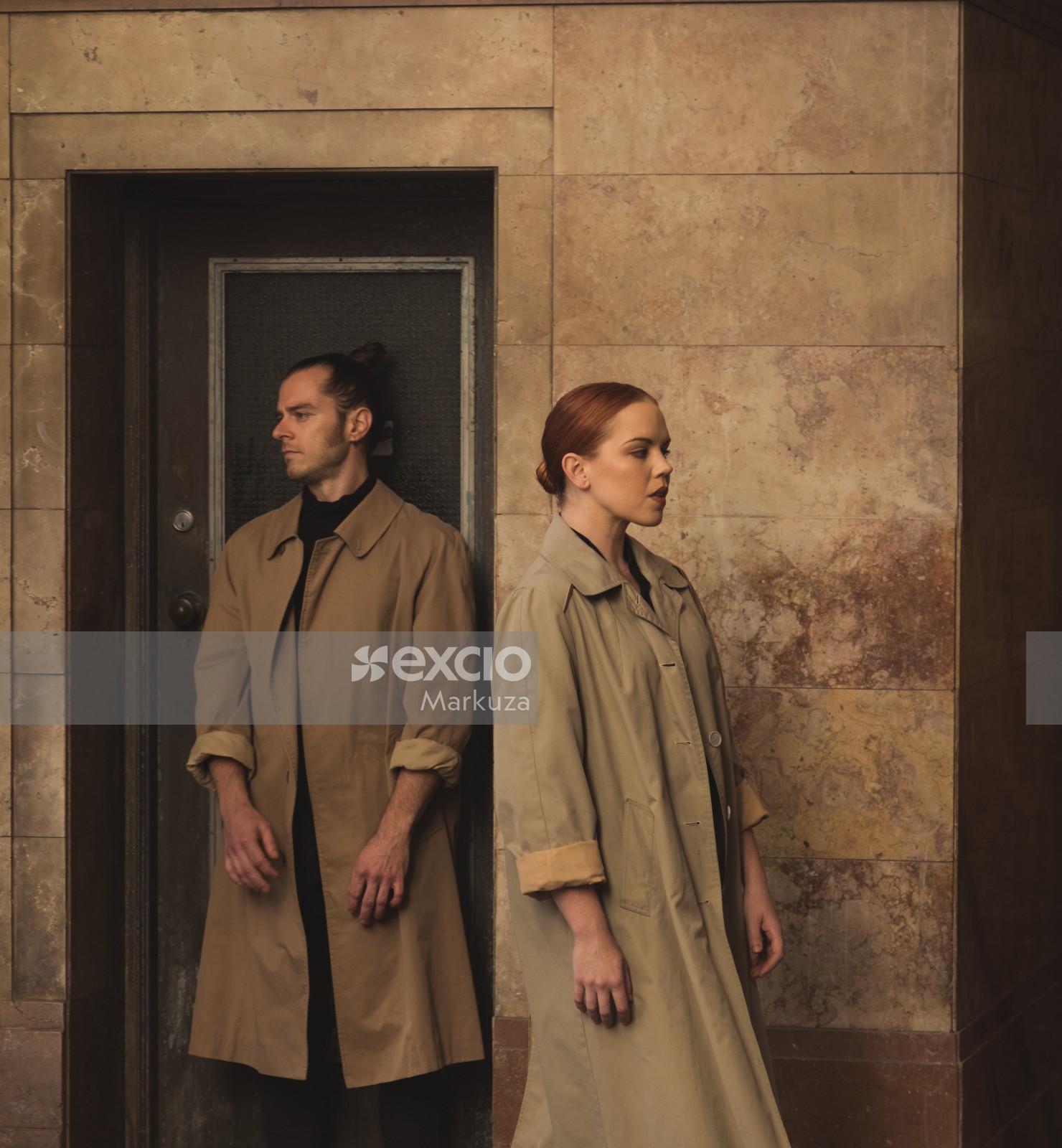 Man and woman standing infront of a door in trench coats