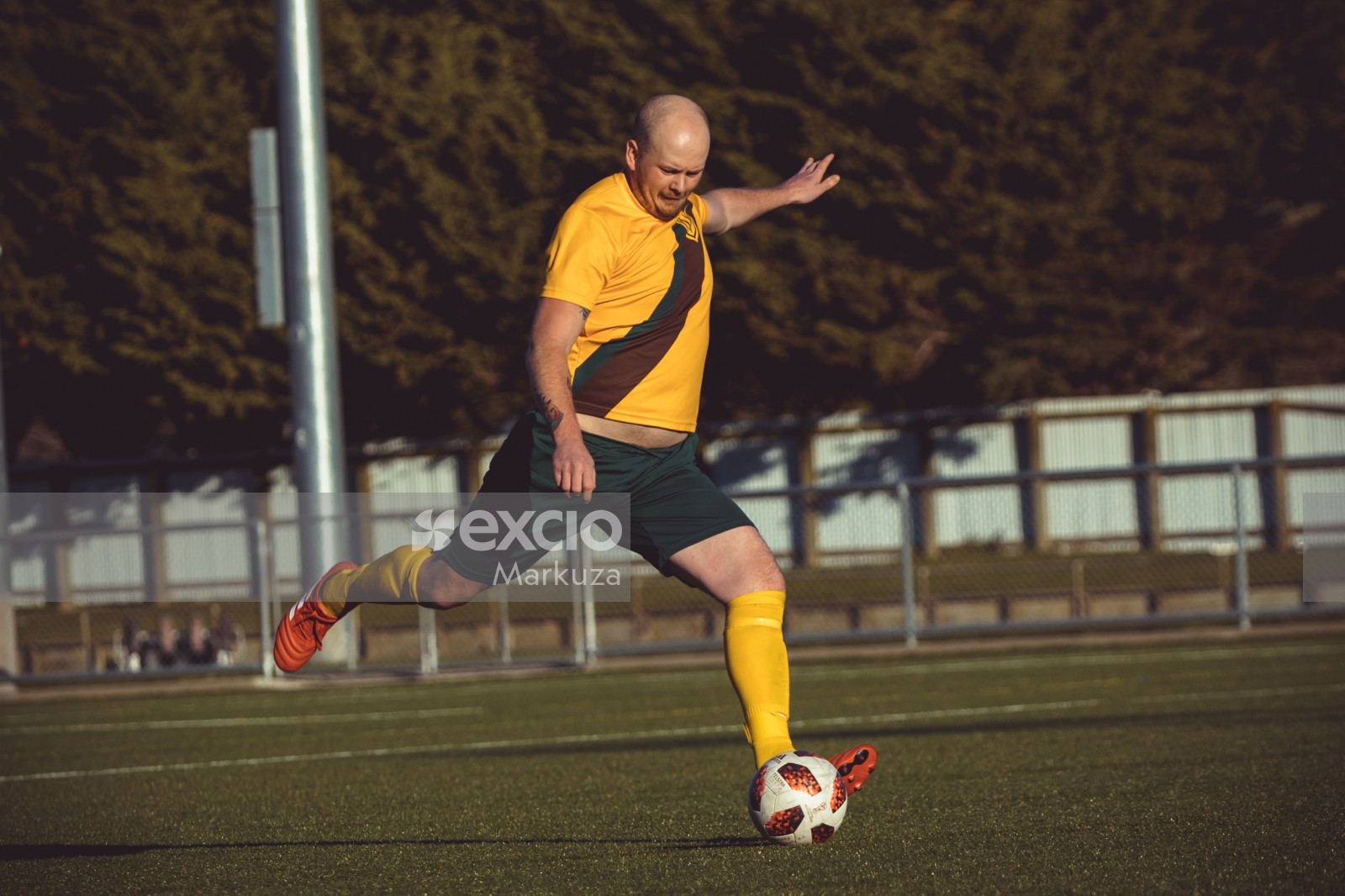 Bald player in orange cleats kicking ball - Sports Zone sunday league