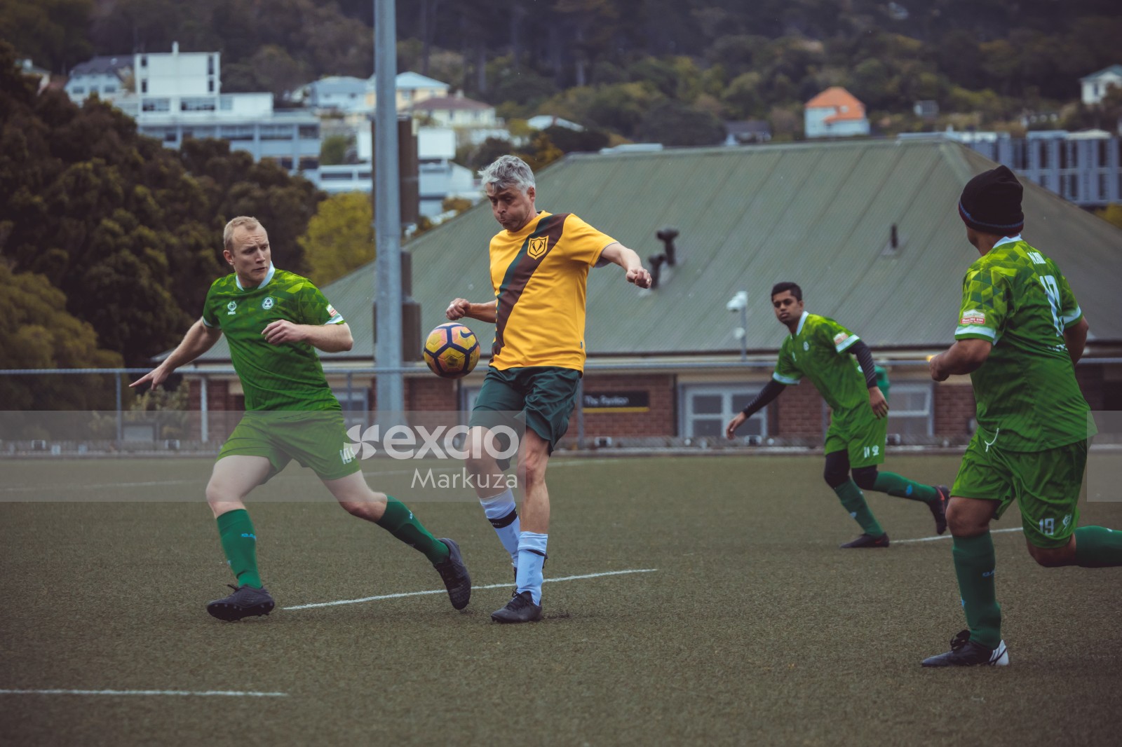 Player in yellow shirt trying to intercept football in mid air - Sports Zone sunday league