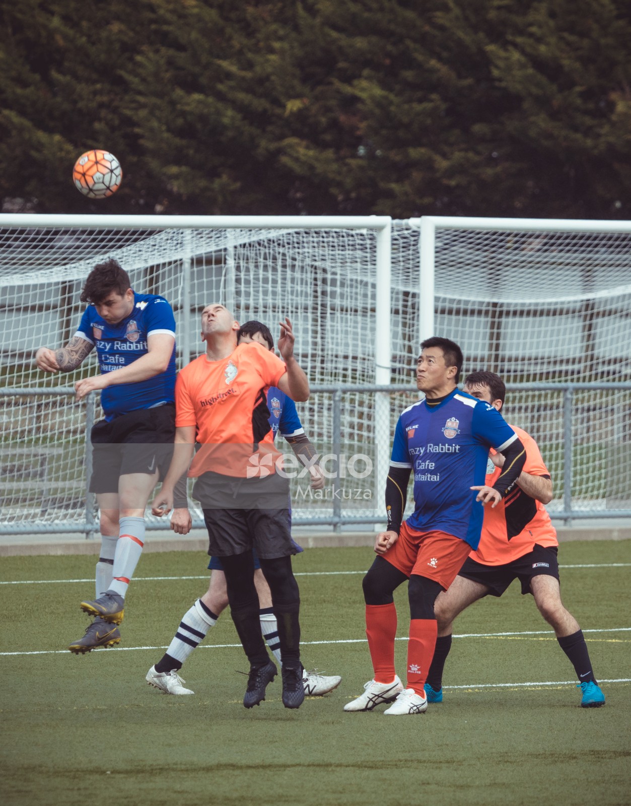 Bald player in orange shirt trying to hit a header - Sports Zone sunday league