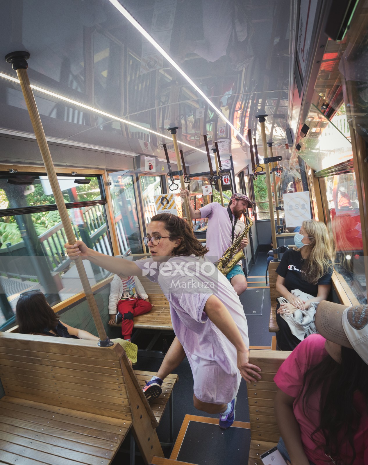 Woman dancing and man playing saxophone in a cable car